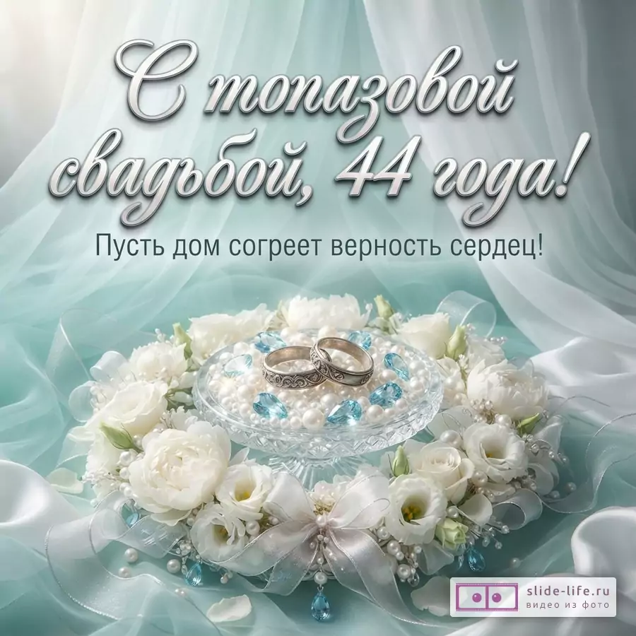 Белый фон, бирюзовая ткань, белые цветы, кольца на подставке с жемчугом и голубыми камнями. Текст: «С топазовой свадьбой, 44 года! Пусть дом согреет верность сердец!»