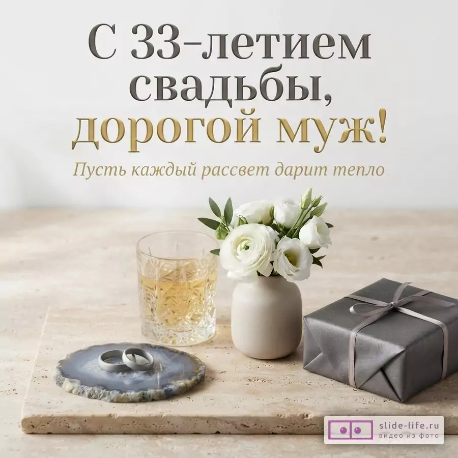 Белый фон, бежевая столешница. На столе стакан с напитком, ваза с белыми цветами, серая подарочная коробка, подставка из агата с двумя кольцами. Текст: «С 33-летием свадьбы, дорогой муж! Пусть каждый рассвет дарит тепло»