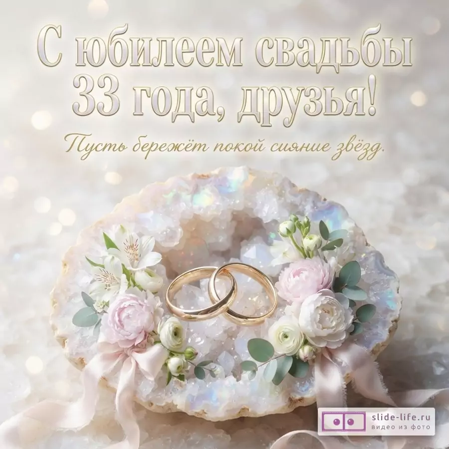 Светлый фон с боке, сверху текст «С юбилеем свадьбы 33 года, друзья! Пусть бережёт покой сияние звёзд.». В центре композиция из двух золотых обручальных колец, лежащих в друзе из светлых кристаллов, украшенной белыми и розовыми цветами, зелёными листьями и розовыми лентами.