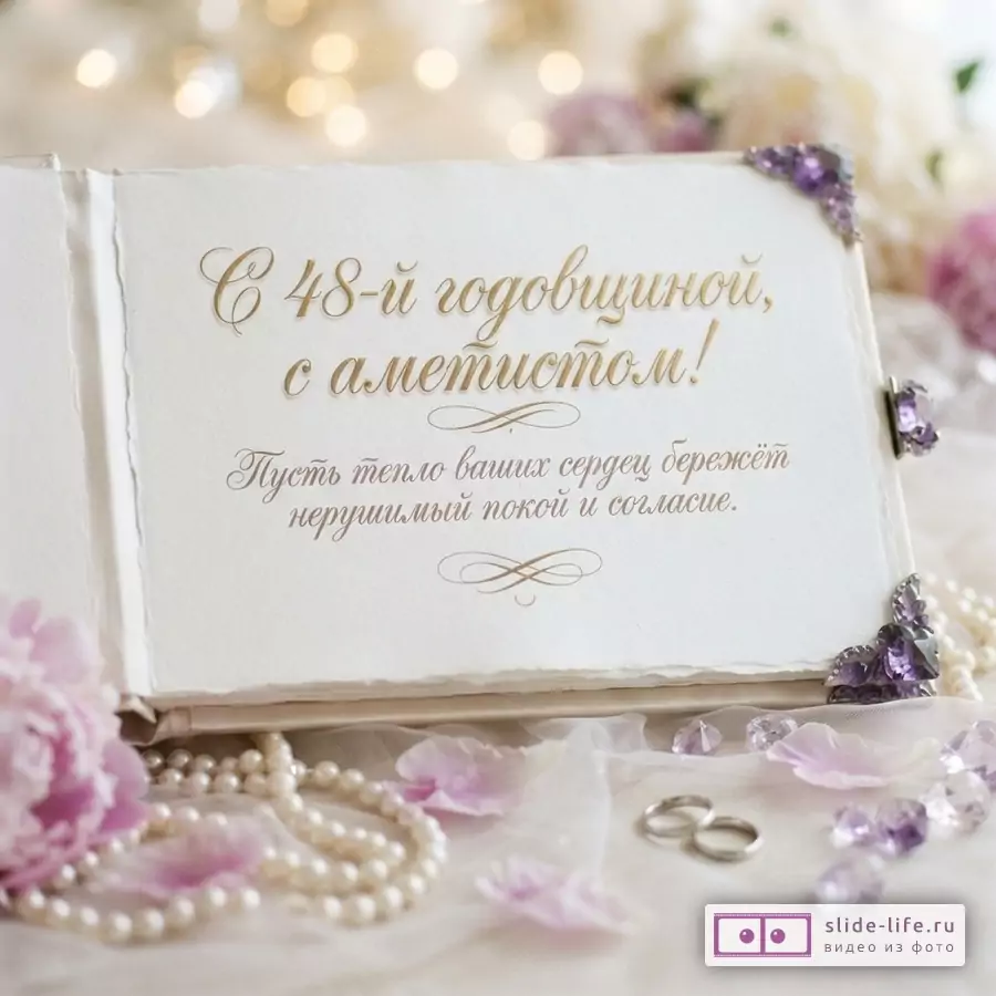 Белый фон, открытка с золотым текстом «С 48-й годовщиной, с аметистом! Пусть тепло ваших сердец бережёт нерушимый покой и согласие.», жемчужное ожерелье, фиолетовые лепестки, аметистовые камни, два обручальных кольца.